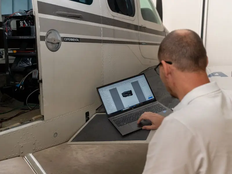 Engineer working on a laptop beside an aircraft during a test