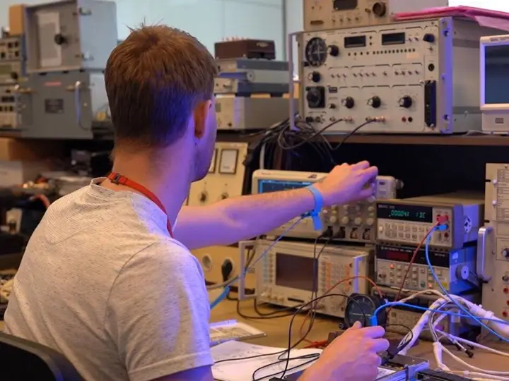 Technician adjusting instruments at a rack of avionics test equipment