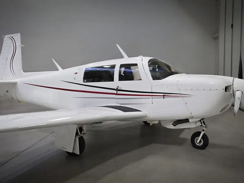 Mooney in a hangar with a thin red stripe livery