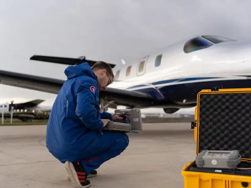 Engineer crouching beside an aircraft with a rugged case of test equipment