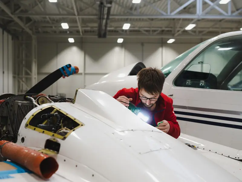 Technician inspecting the open nose bay of an aircraft with a torch