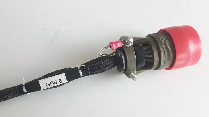 Braided wiring harness with a circular connector and red protective cap