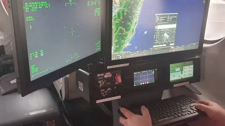 Operator workstation with two displays and the mission control unit inside the cabin of a special-mission aircraft