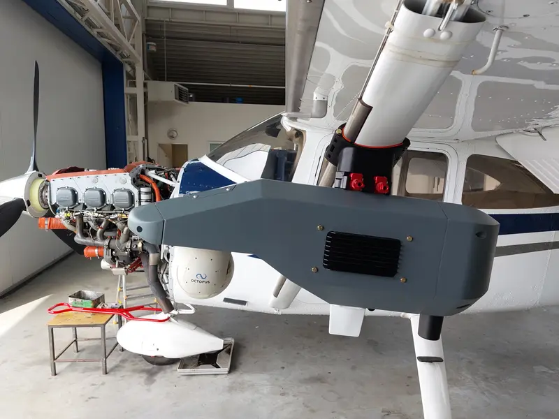 Cessna in the hangar with a grey sensor pod mounted under the wing