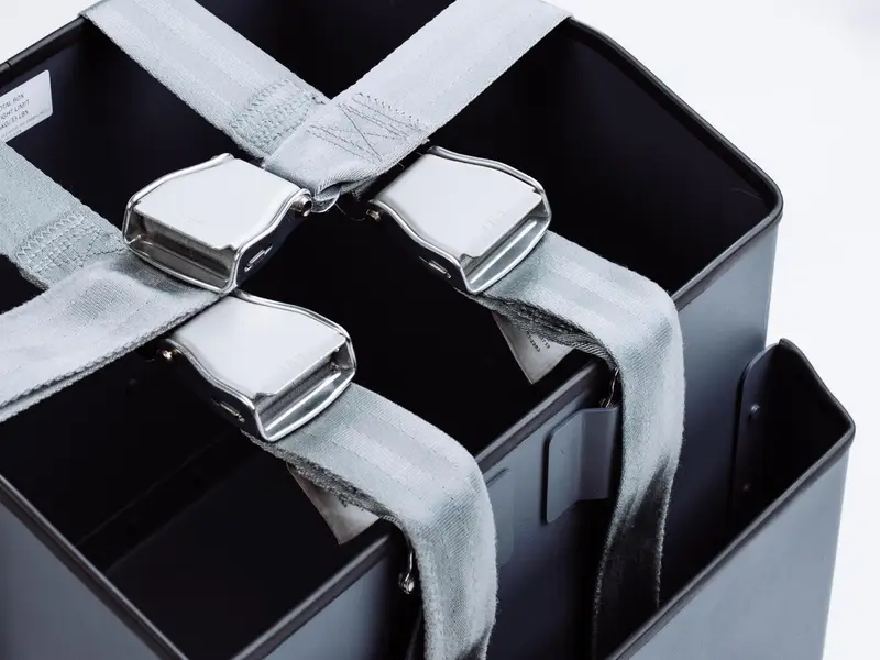 Black stowage bins with grey seat-belt straps and buckles
