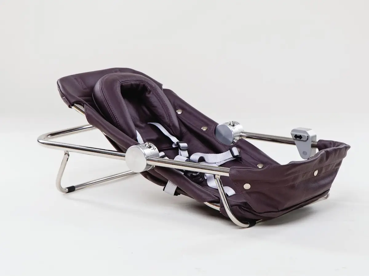 Baby cradle with a tubular metal frame and dark fabric cover