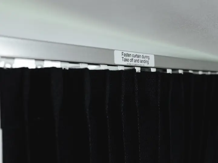 Black fabric curtain with a label about fastening during take-off and landing
