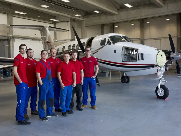 AIR TEAM staff lined up next to a King Air with the hangar doors open