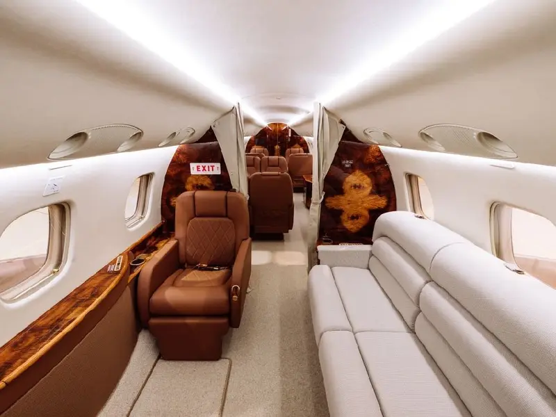 Business jet cabin seen from the aisle with seats and a divan